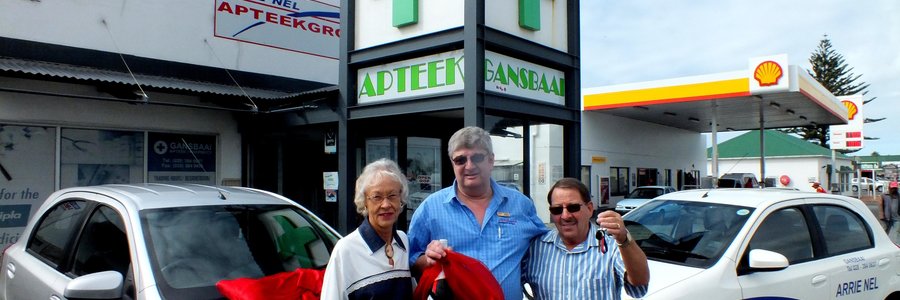 â€˜n Dankbare Gerhard Roux (regs) van Franskraal, nadat hy â€˜n Toyota Etios 1.5ltr van Arrie Nel Apteekgroep gewen het, met vlnr Angeline Roux (sy eggenote) en Fanie Viljoen (Apteker/Bestuurder: Gansbaai Apteek) by hom voor Gansbaai Apteek